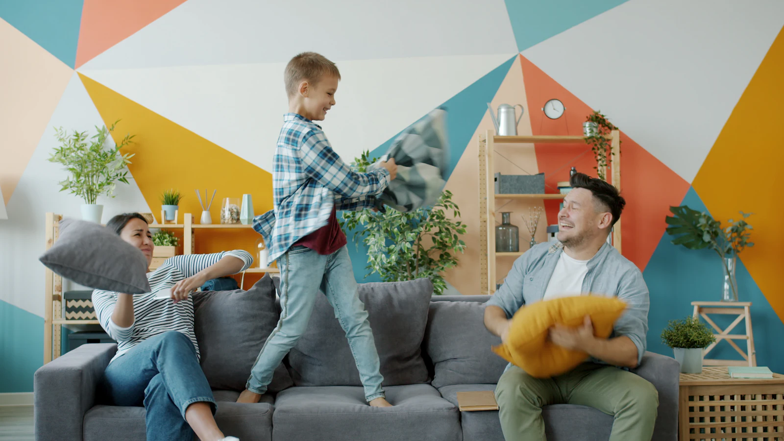 Une famille en pleine bataille de coussins dans le salon