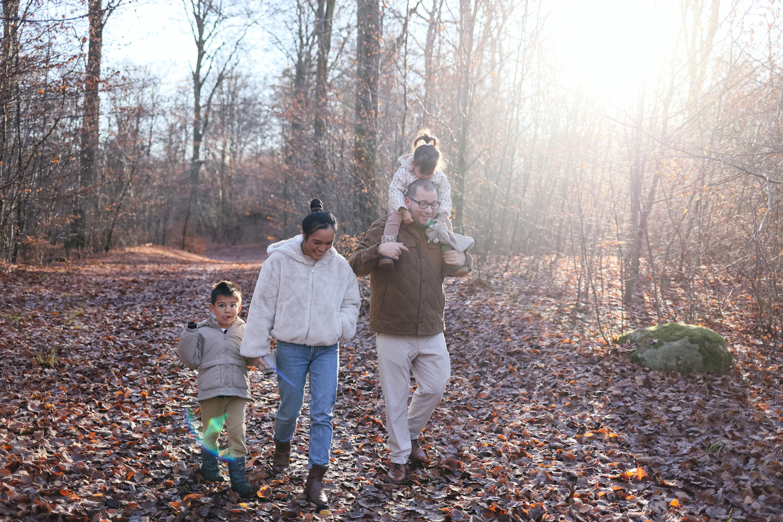 Une famille se promène sur un chemin couvert de feuilles d’automne