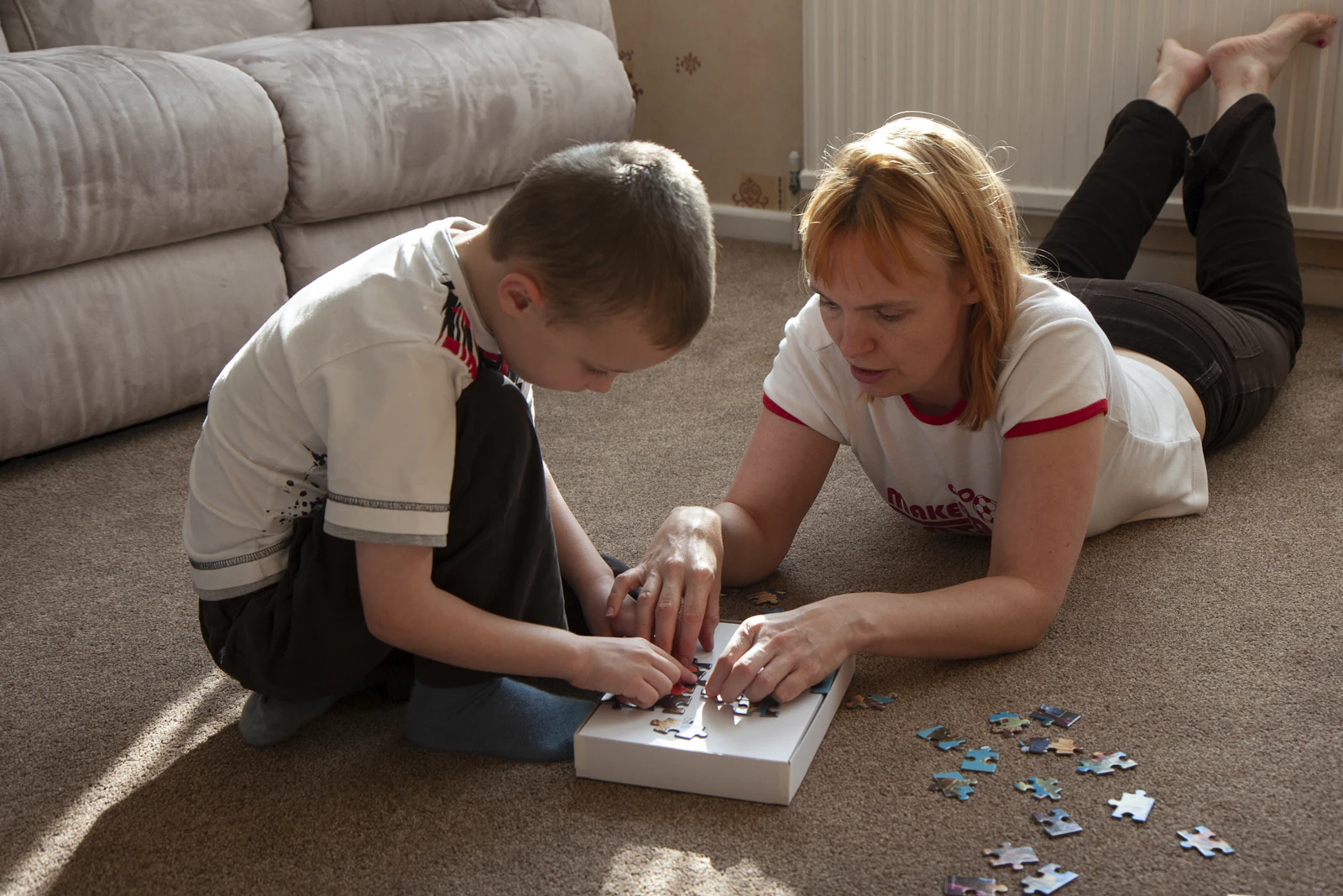 Une maman et son fils font un puzzle sur le tapis